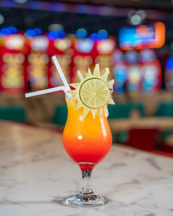 RKitchen's Tequila Sunrise, vibrant colourful drink garnished with a sun shaped lime.